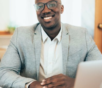 Shot of a young businessman sitting on desk in modern office and looking at camera